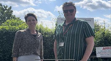 Female and male council staff members in front of hedge