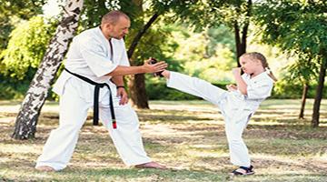 White man and white female child practicing karate in a field