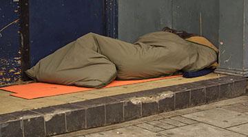 A person with their back to the camera in a sleeping bag on a step